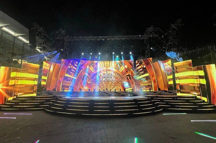 Colorful stage set up for miss global event with vibrant lighting and geometric shapes.